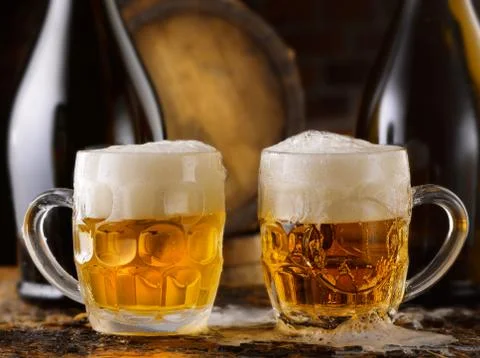 Frothy mug of beer set in a rustic cellar Stock Photos