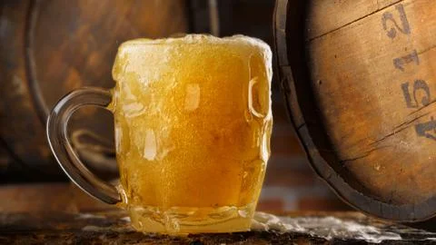 Frothy mug of beer set in a rustic cellar Stock Photos