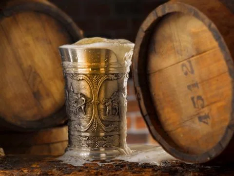 Frothy mug of beer set in a rustic cellar Stock Photos