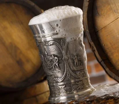Frothy mug of beer set in a rustic cellar Stock Photos