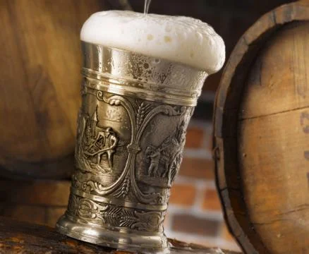 Frothy mug of beer set in a rustic cellar Stock Photos