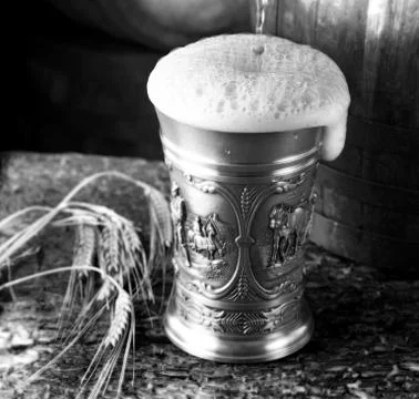 Frothy mug of beer set in a rustic cellar Stock Photos