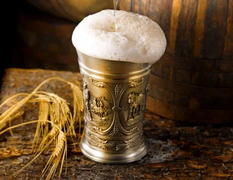 Frothy mug of beer set in a rustic cellar Stock Photos