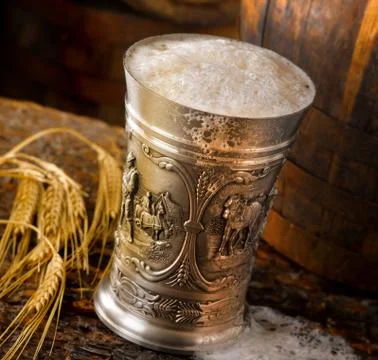 Frothy mug of beer set in a rustic cellar Stock Photos
