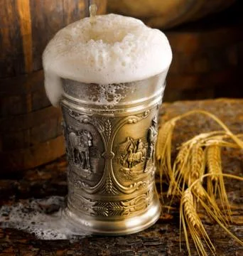Frothy mug of beer set in a rustic cellar Stock Photos