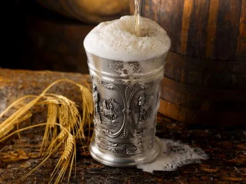 Frothy mug of beer set in a rustic cellar Stock Photos