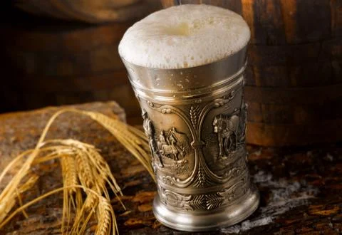 Frothy mug of beer set in a rustic cellar Stock Photos
