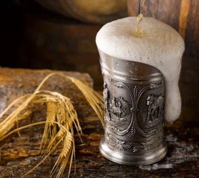 Frothy mug of beer set in a rustic cellar Stock Photos