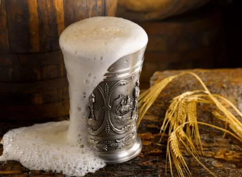 Frothy mug of beer set in a rustic cellar Stock Photos