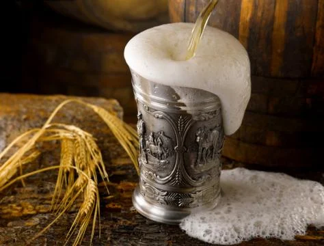 Frothy mug of beer set in a rustic cellar Stock Photos