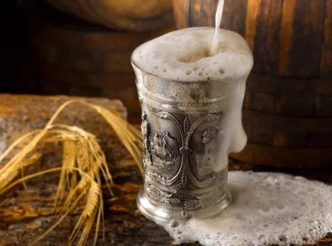 Frothy mug of beer set in a rustic cellar Stock Photos