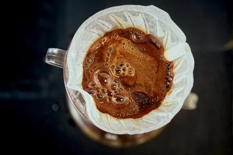 A frothy shot of espresso in a paper filter. Method of brewing filter coffee Stock Photos