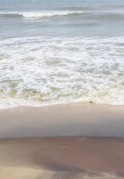 Frothy waves on beach with patterns Stock Photos