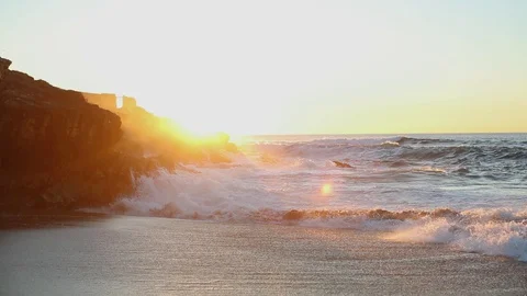 Frothy waves break against a rocky rock on the ocean at sunrise Stock Footage 130001543