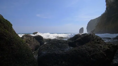 Frothy waves breaking over rocks in an Indonesian bay Stock Footage 93781714
