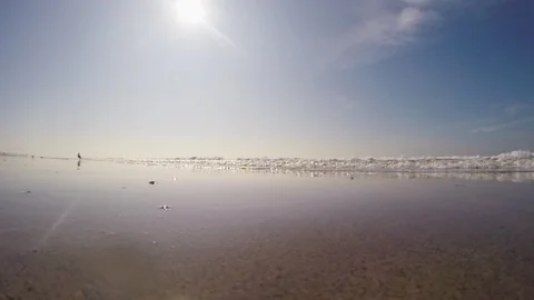 Frothy waves reaching beach on a sunny day Stock Footage 108544133
