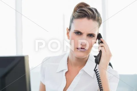 Frowning classy businesswoman talking on the phone Stock Photos