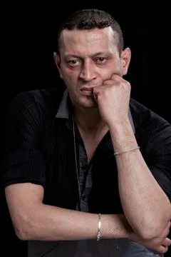 Frowning man portrait looking at camera on black background Stock Photos