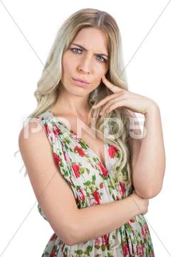 Frowning pretty blonde wearing flowered dress posing Stock Photos