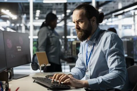 Frowning programmer in server room worried by critical hardware error on PC Stockfoto's
