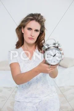 Frowning tired woman showing alarm clock Stock Photos