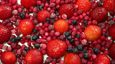 Frozen blueberries fall on red berries decorating the top of cheesecake Vídeos de archivo 243435792
