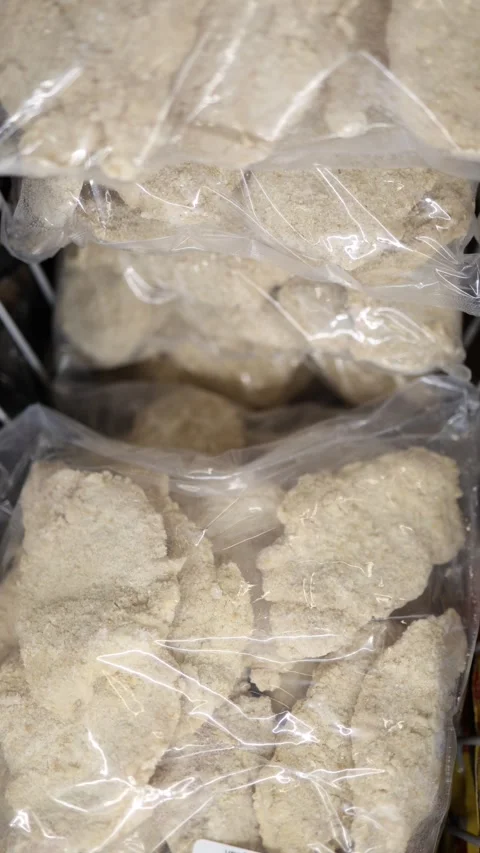 Frozen breaded pork cutlets packaged in plastic bags inside supermarket freezer Stock Footage 345978146