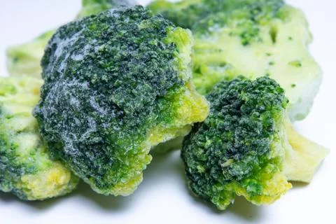 Frozen broccoli close-up on white background. Stock Photos