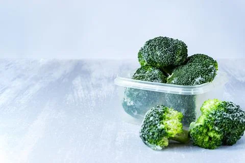 Frozen broccoli in a plastic box on grey table, copy space Foto stock