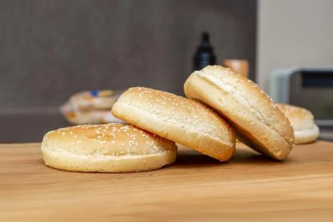 Frozen buns for a burger lie in a stack on a wooden cutting board, the proces Foto stock