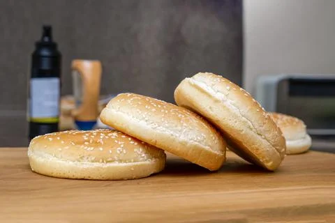 Frozen buns for a burger lie in a stack on a wooden cutting board, the proces Stock Photos