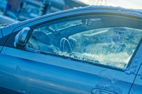 Frozen car window with ice and snow on a cold winter day outdoors Stock Photos