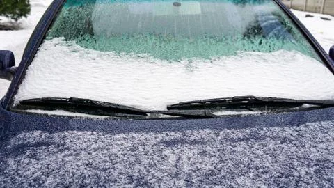 Frozen car windshield covered with ice and snow on a winter day. Close-up vie Stock Photos