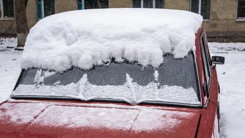 Frozen car windshield covered with ice and snow on a winter day. Close-up vie Stock Photos