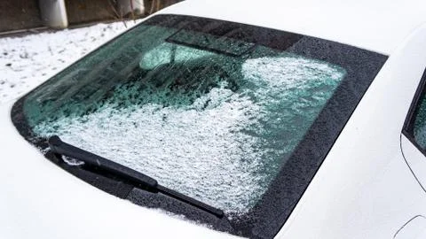 Frozen car windshield covered with ice and snow on a winter day. Close-up vie Stock Photos