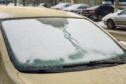 Frozen car windshield covered with ice and snow on a winter day. Close-up vie Stock Photos