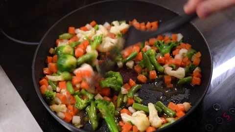 Frozen chopped vegetables are cooked in frying pan and stirred with spatula Vidéo 232892834