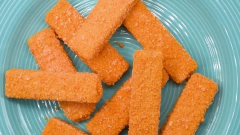 Frozen cod fish fingers rotating on a blue plate. Breaded seafood sticks ready Stock Footage 321499234