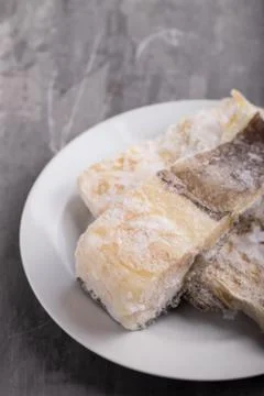 Frozen cod fish on white dish on ceramic background Stock Photos
