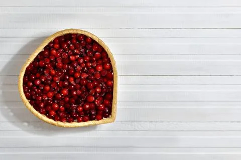 Frozen cranberries in a wicker dish in the shape of a heart. Stock Photos