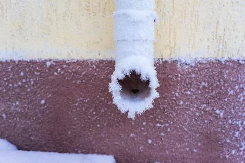 Frozen downpipe. .White downpipe on the wall covered with frost Stock Photos