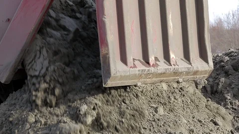 Frozen earth pours from back of large truck onto ground, construction site Stock Footage 115925274
