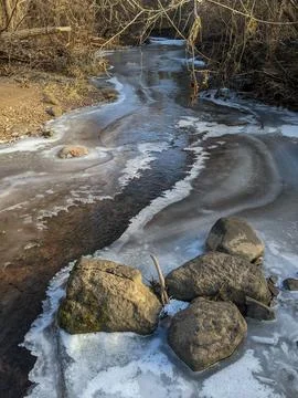 Frozen Forest Stream and Rocks in Winter Under Afternoon Sunlight Fotos Stock