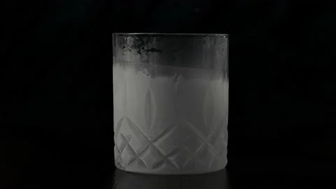 A frozen glass of whiskey stands statically on a black background. Stock Footage