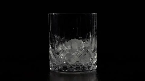 A frozen glass of whiskey stands statically on a black background. Stock Footage