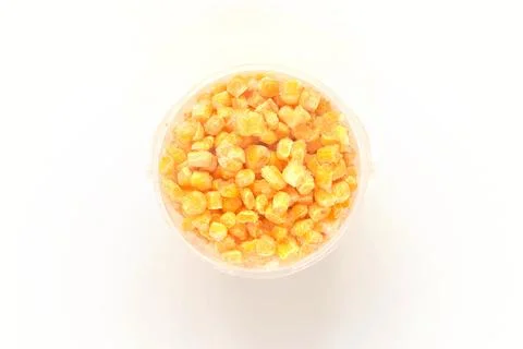 Frozen grains of corn on a white isolated background in a plastic container.  Stock-Fotos