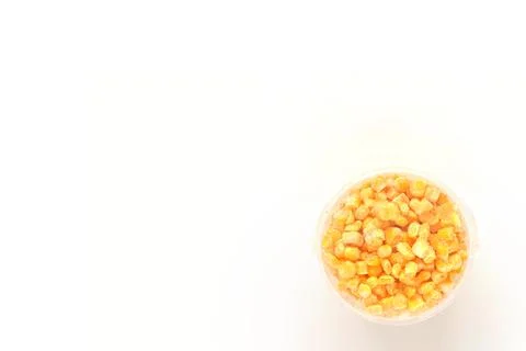 Frozen grains of corn on a white isolated background in a plastic container.  Stock Photos