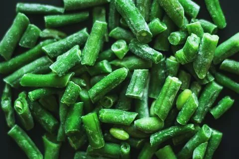 Frozen green useful string beans lie on a black background. Ingredient for th Stock Photos