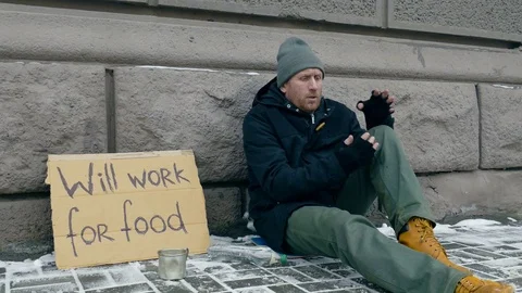 Frozen homeless man warming hands. Sign on cardboard - will work for food. Stock Footage 71399672