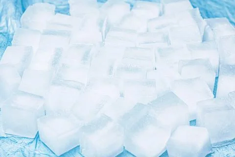 Frozen ice cubes for drinks arranged in a scattered pattern on a blue surface Stock Photos